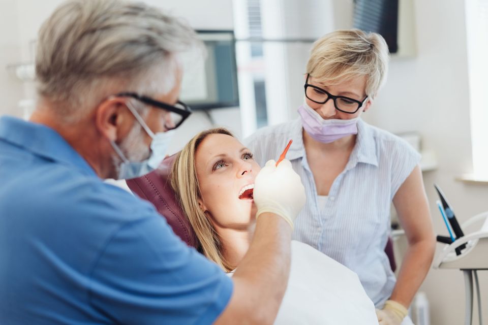 Zahnarzt und Assistentin bei der Behandlung einer Patientin